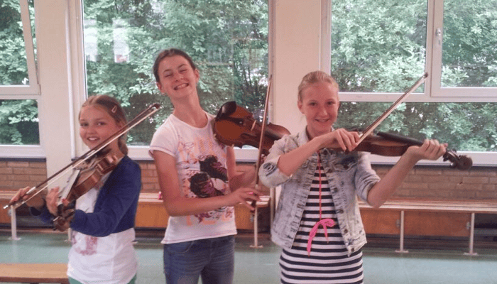 Kinderen volgen samen vioolles en spelen viool